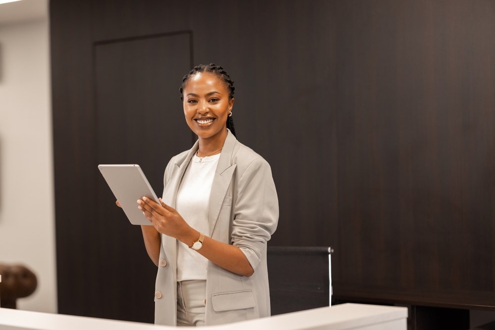 The,Young,African-american,Female,Receptionist,Stands,Behind,The,Reception,Desk